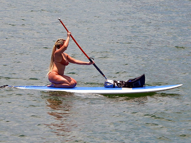 Attractive woman with long braided blond hair rowing a paddle board on the Florida Intra-Coastal Waterway